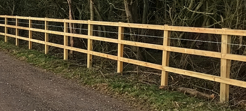 Post and rail perimeter fence with barbed wire installed as a deterrent
