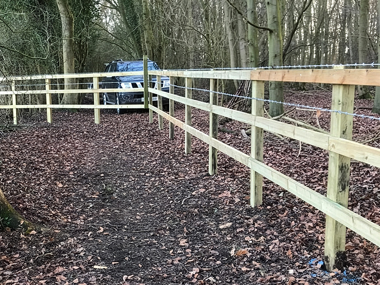 Close-up of post and rail fencing with barbed wire