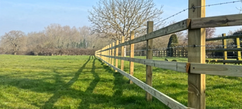 Post and rail fence with barbed wire in rural setting