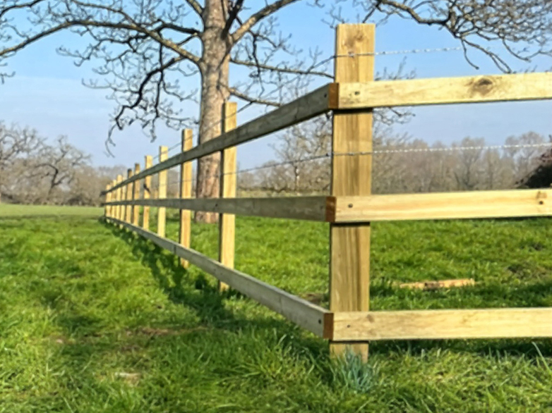 Close-up of timber post and rail fence with barbed wire