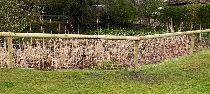 Garden pond fencing with round posts and stock wire