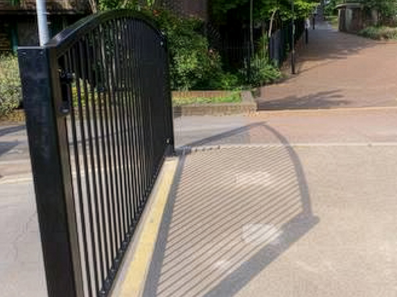 Curved top vertical bar gate securing pedestrian area